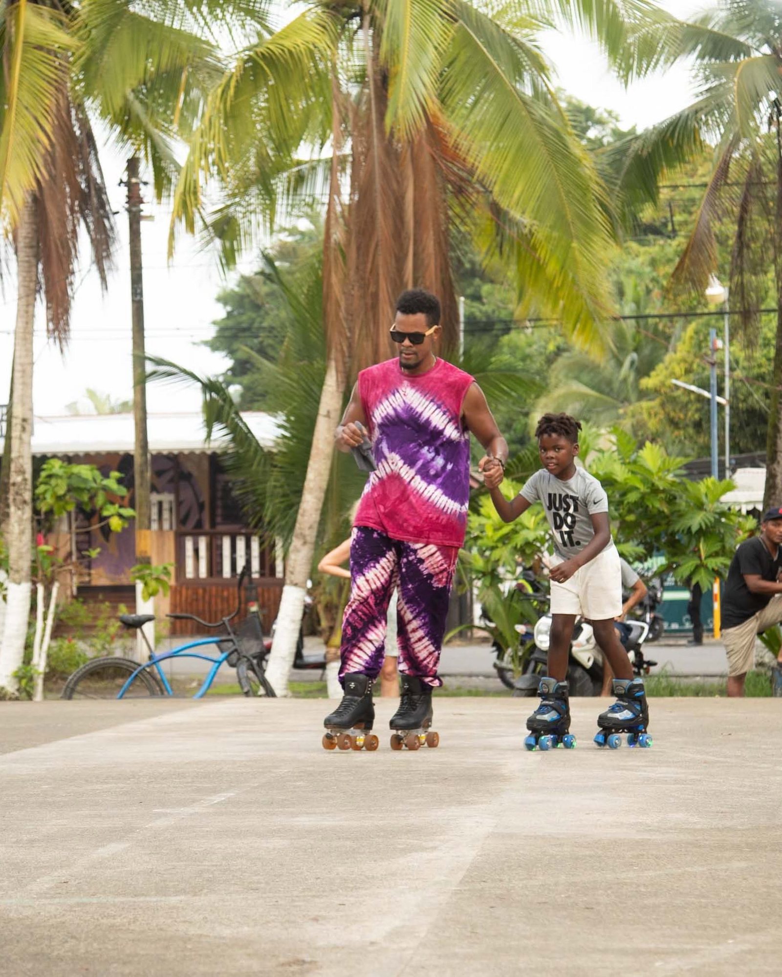 A coach in tie-dye holding hands with a young skater